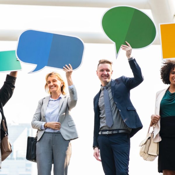 Four well-dressed professionals holding up thought or speech bubble signs