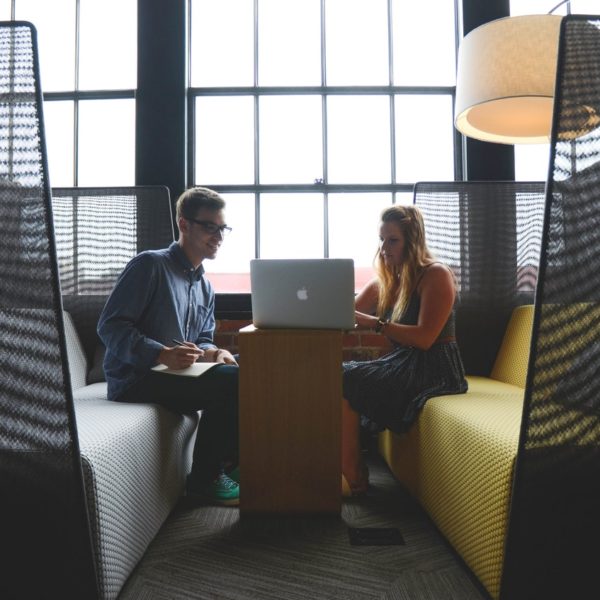 Two young professionals in co-working space looking at laptop