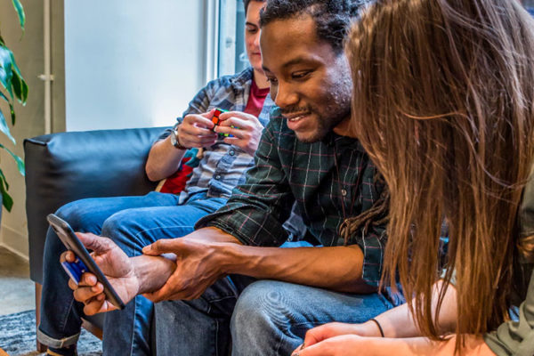 Three people chatting and looking at cell phone screen