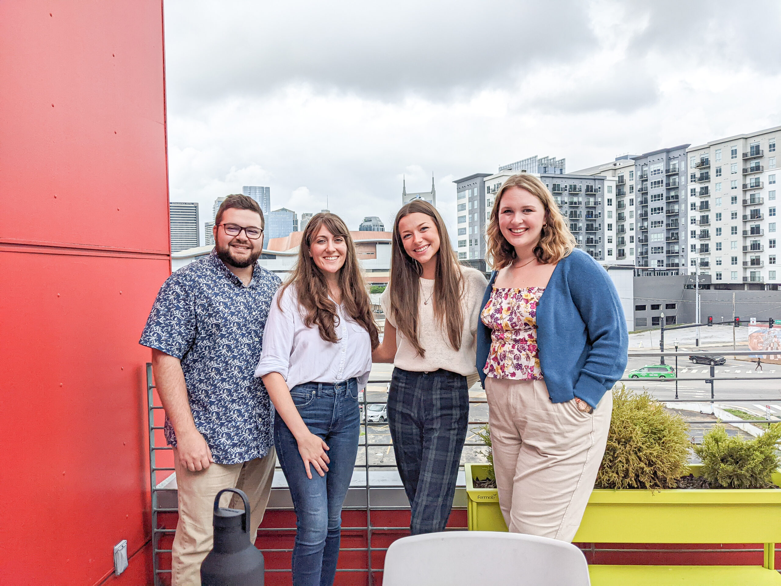 Four Piccolo team members smiling on a balcony