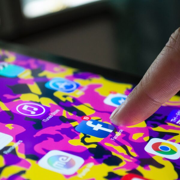 Social media apps on phone. Finger is pressing on Facebook app.